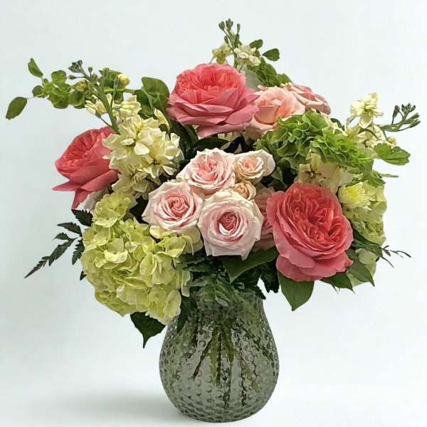 Pink roses and green hydrangeas in a textured glass vase