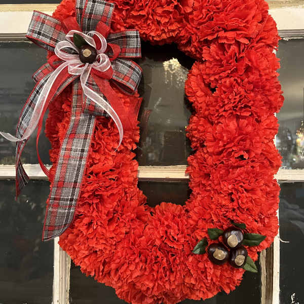 Red carnation wreath with plaid ribbon bow on a window