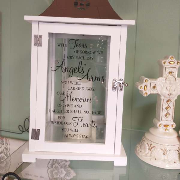 White memorial lantern with a sympathy quote and a decorative cross beside it