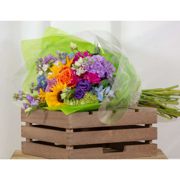 Colorful bouquet of mixed flowers wrapped in green and clear plastic