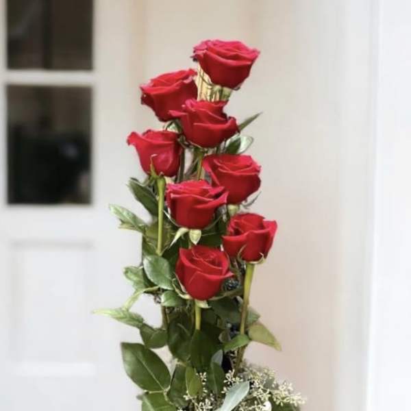 Tall arrangement of red roses in a silver vase