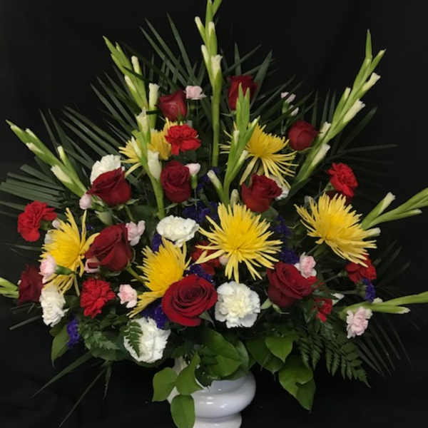 Red roses and yellow spider mums in a white vase