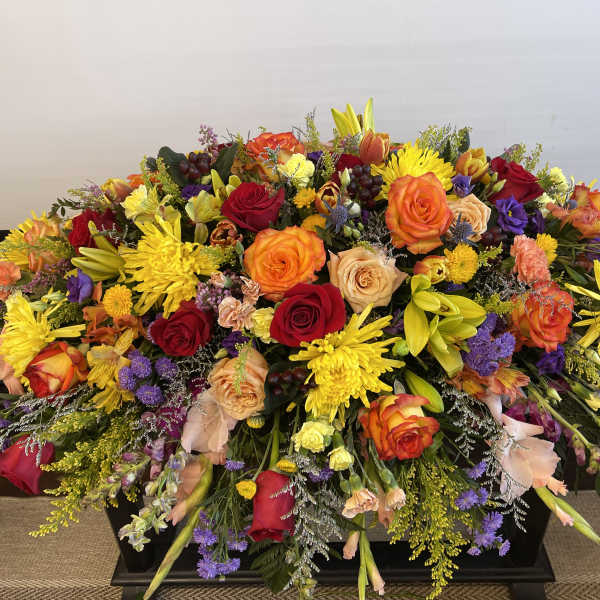 Large casket spray with roses, lilies, and chrysanthemums in bright mixed colors