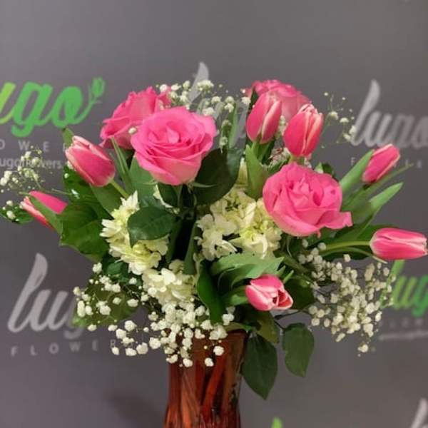 Pink roses and tulips arranged in a red glass vase
