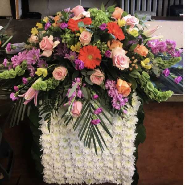 Large funeral spray with pink roses, gerbera daisies, and white chrysanthemums