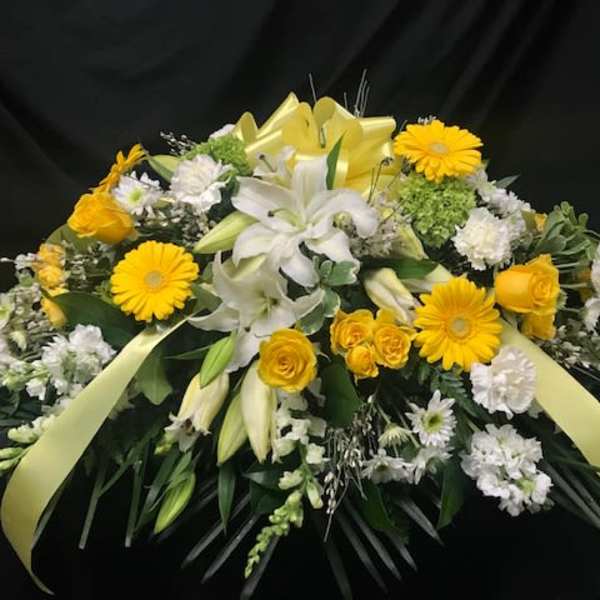 Yellow and white floral spray with lilies, roses, and daisies