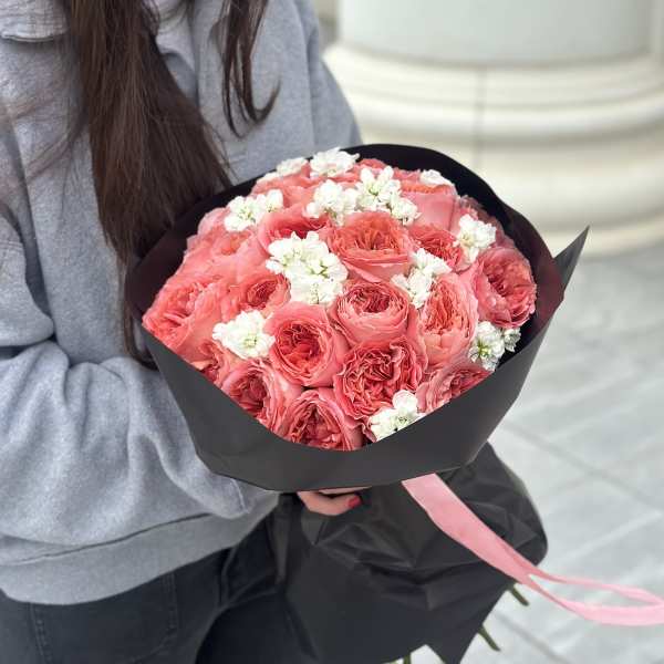 Bouquet of pink roses with small white flowers wrapped in black paper
