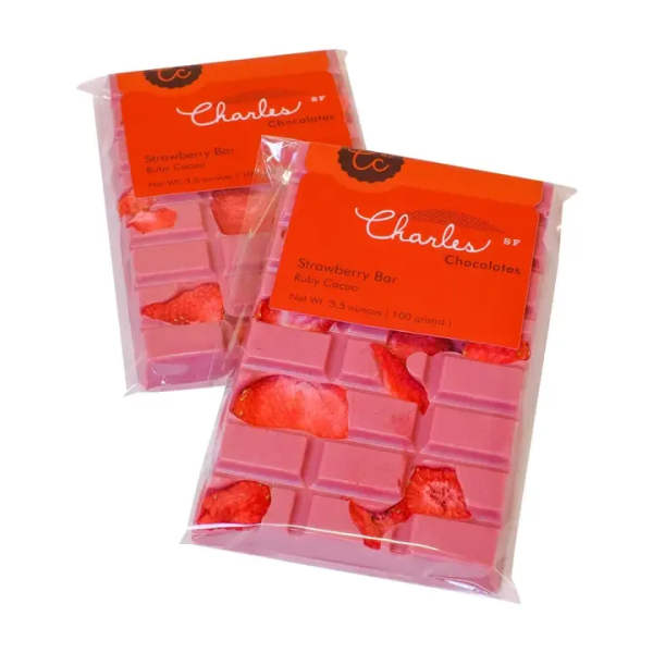 Two packaged pink strawberry chocolate bars with red labels.