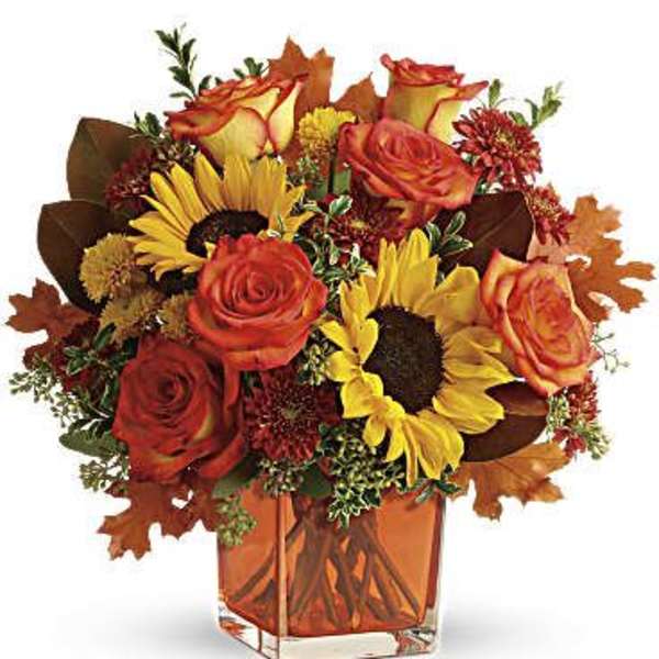 Bouquet of orange roses and sunflowers in a square glass vase