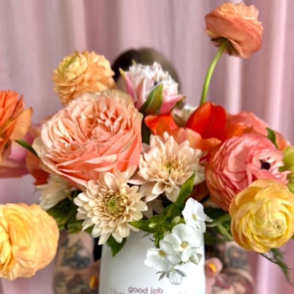 Bouquet of peach, pink, and yellow flowers in a white mug