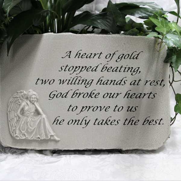 Memorial plaque with an angel relief and engraved text, framed by greenery