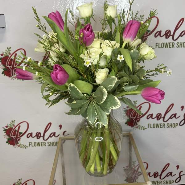 Pink and white tulips with white roses in a glass vase