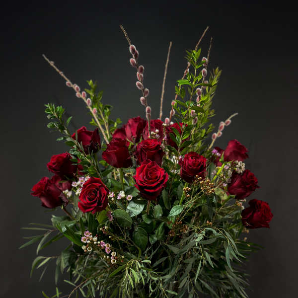 Tall bouquet of red roses with greenery in a glass vase