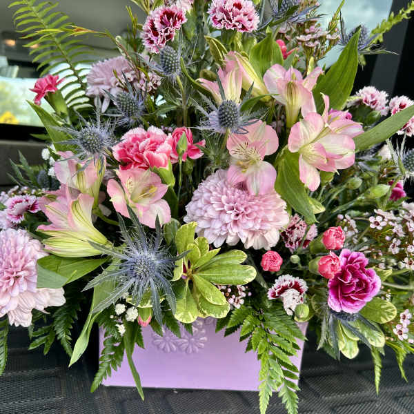 Pink and lavender mixed flower arrangement in a lavender container