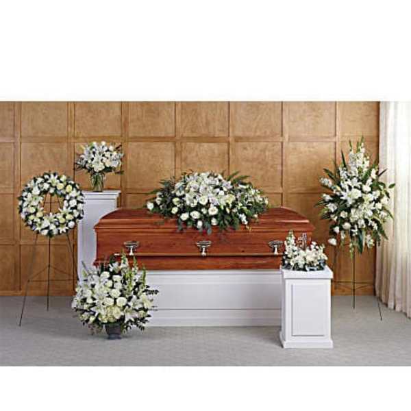 White funeral casket surrounded by white floral sprays and wreaths