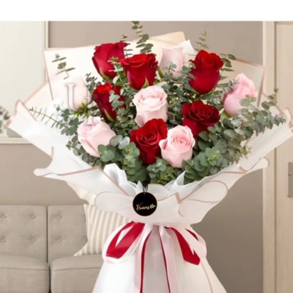 Bouquet of red and pale pink roses wrapped in white paper