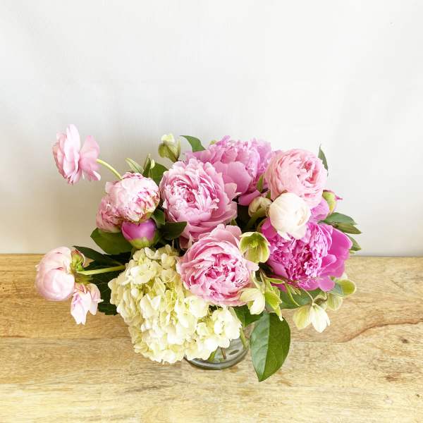 Pink peonies and hydrangea in a clear glass vase