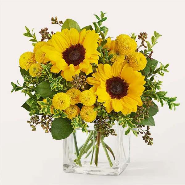 Sunflower and yellow pom bouquet in a clear glass vase