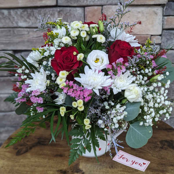 Mixed bouquet of red and white flowers in a white vase