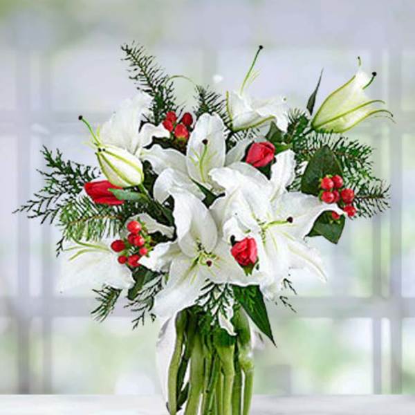 White lilies and red roses in a clear glass vase