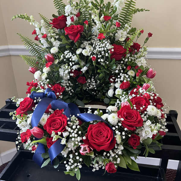 Standing red and white floral spray with matching wreath of roses and tulips and a blue ribbon.