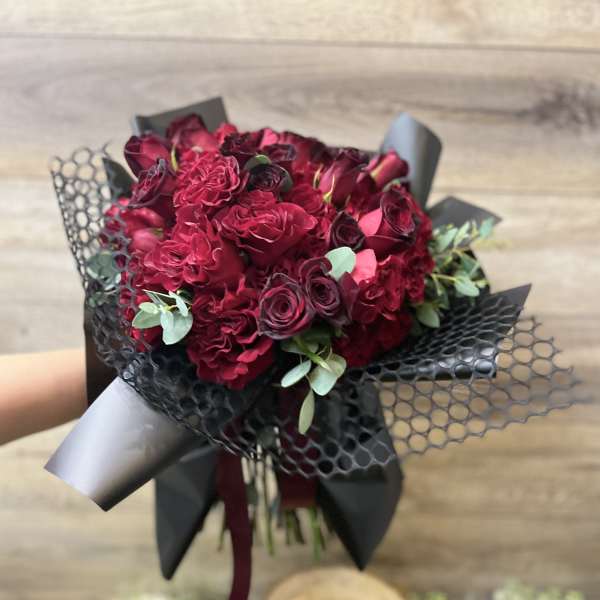 Bouquet of deep red roses wrapped in black paper