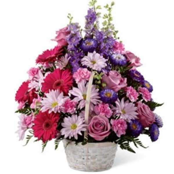 Mixed pink and purple flowers arranged in a white basket