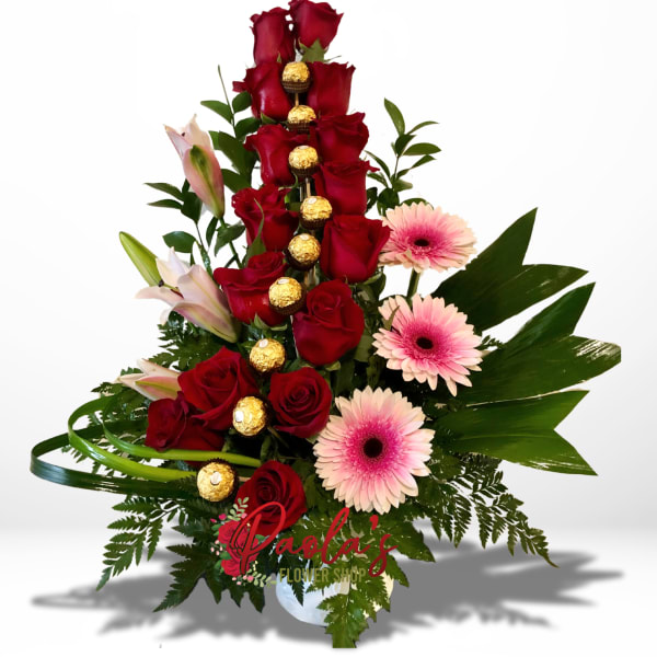 Tall arrangement of red roses, pink gerberas, and lilies with chocolates