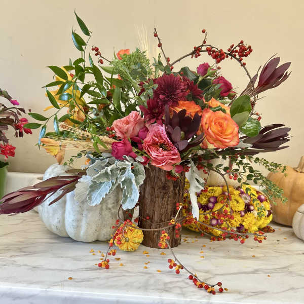 Mixed floral arrangement with pink and orange roses in a wood vase