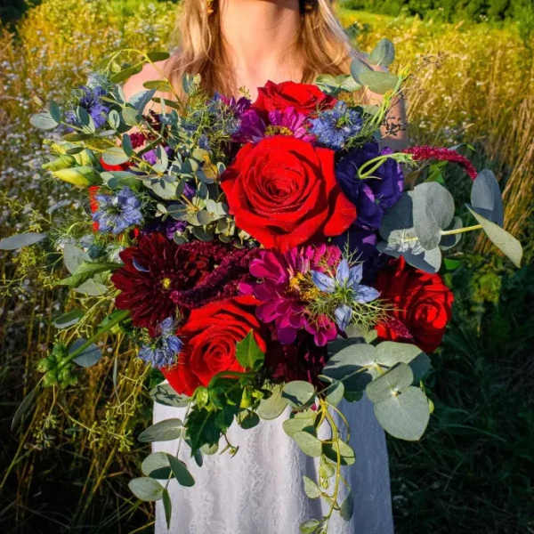 Woman holding a bouquet of red roses and purple flowers