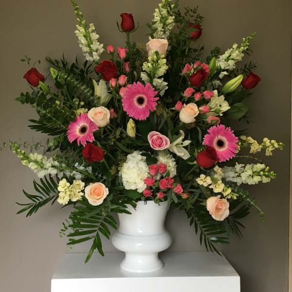Large mixed flower arrangement in a white urn vase