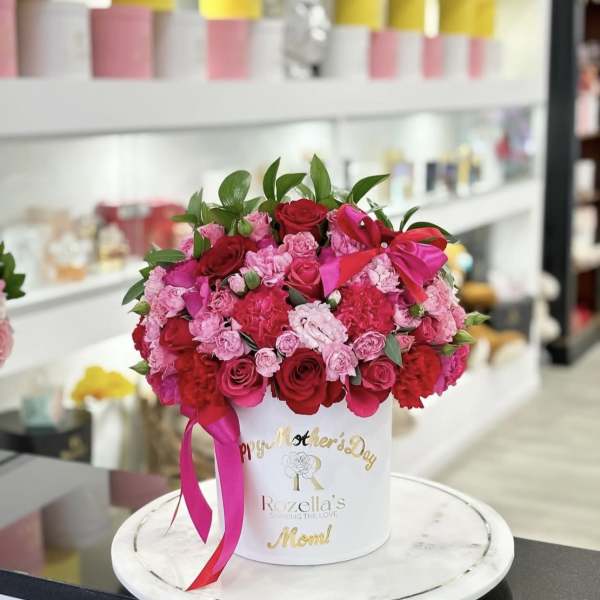 Pink and red rose arrangement in a white hat box with a ribbon