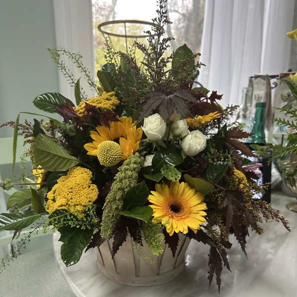 Mixed yellow and white flowers arranged in a metal basket