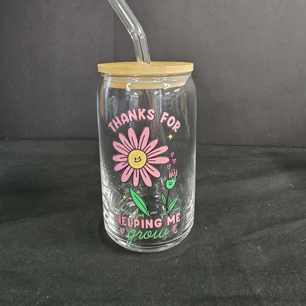 Clear glass tumbler with bamboo lid and straw, decorated with a pink daisy graphic
