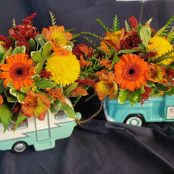Two floral arrangements in turquoise truck containers with orange and yellow blooms