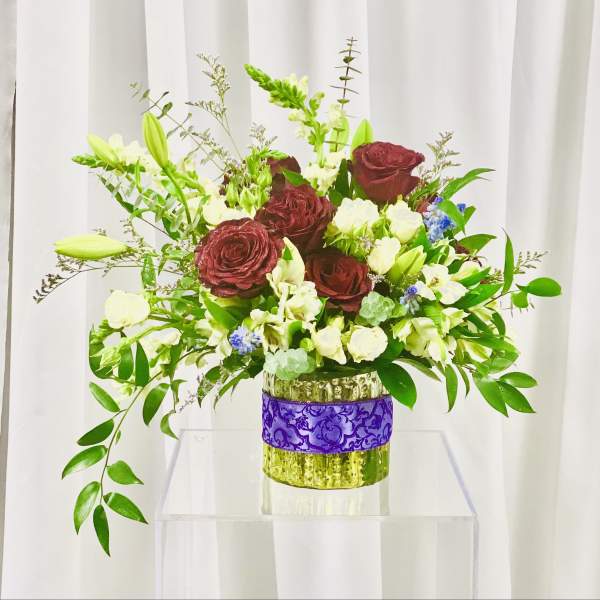 Bouquet of burgundy roses and white flowers in a glass vase
