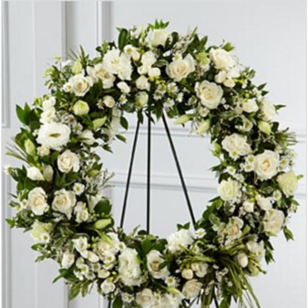 Large white rose and daisy wreath displayed on a metal easel stand.