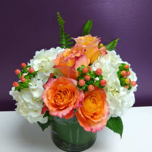 Orange roses and white hydrangeas in a glass vase