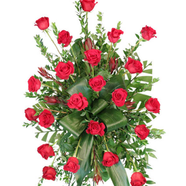 Tall standing spray of red roses with structured green leaves on a metal easel.