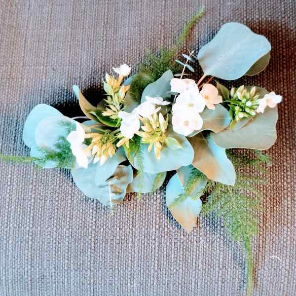 Small floral arrangement with white blossoms and blue-green leaves on a textured surface