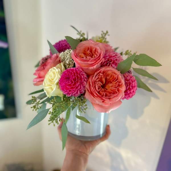 Pink and coral roses with magenta blooms in a silver vase