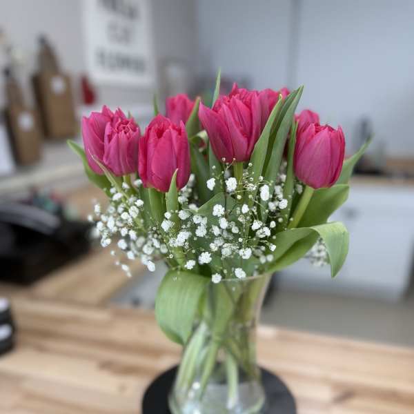 Pink tulips in a clear glass vase with white baby's breath
