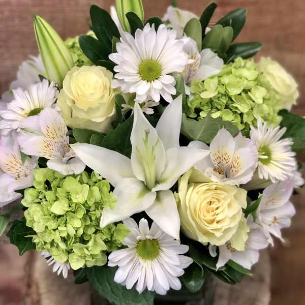 Bouquet of white lilies, pale yellow roses, and daisies with green hydrangea