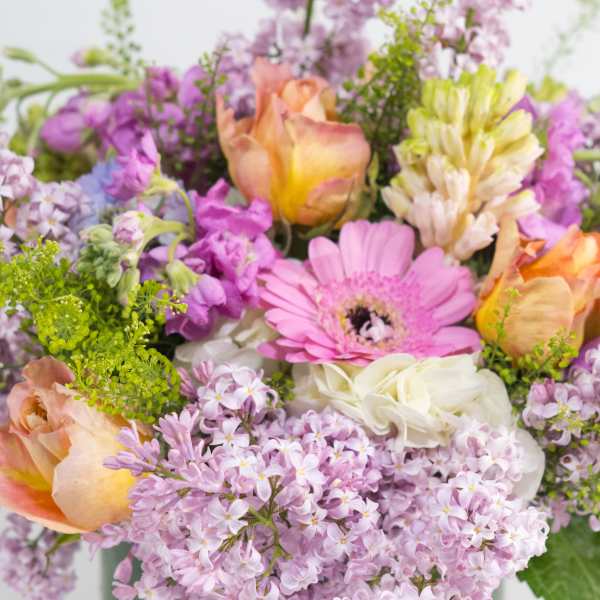 Mixed bouquet with pink gerbera daisies, peach roses, and lilac flowers