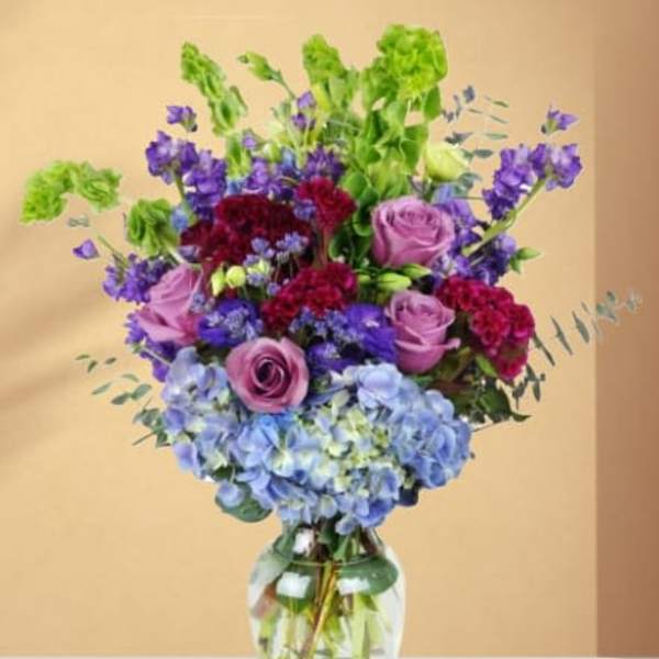Bouquet of purple and blue flowers in a clear glass vase