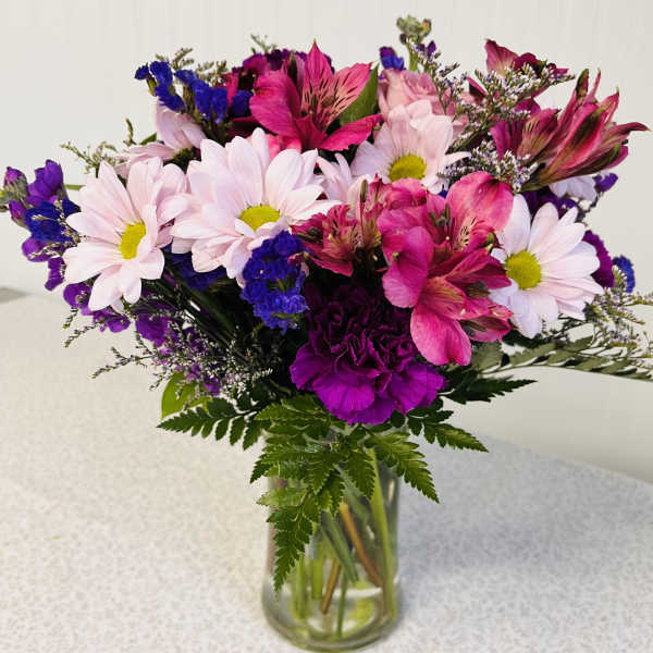 Bouquet of pink daisies and magenta alstroemeria in a glass vase
