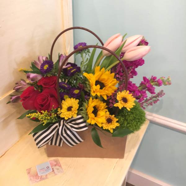 Mixed flower arrangement in a brown handled box with a striped ribbon