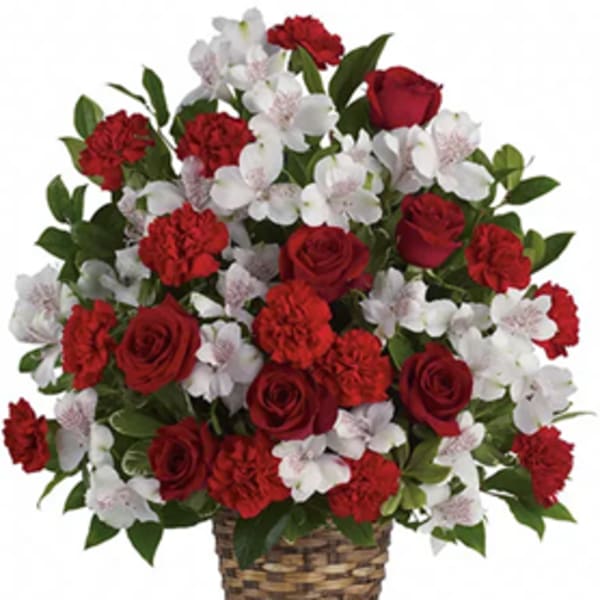 Red roses and carnations with white blossoms in a woven basket