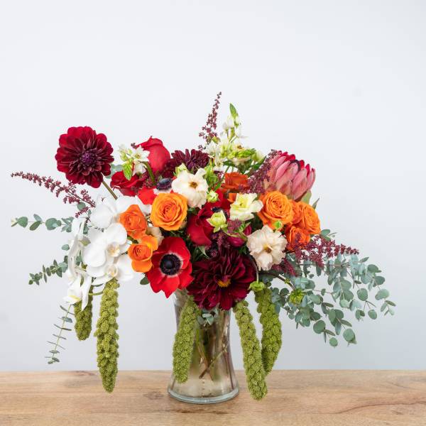 Mixed bouquet in a glass vase with red, orange, white, and pink blooms