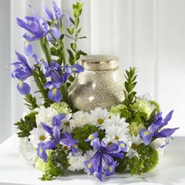 Purple irises and white daisies arranged around a gold urn candle.